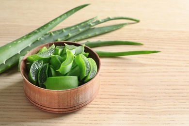 Bowl with sliced aloe vera leaves and space for text on wooden table