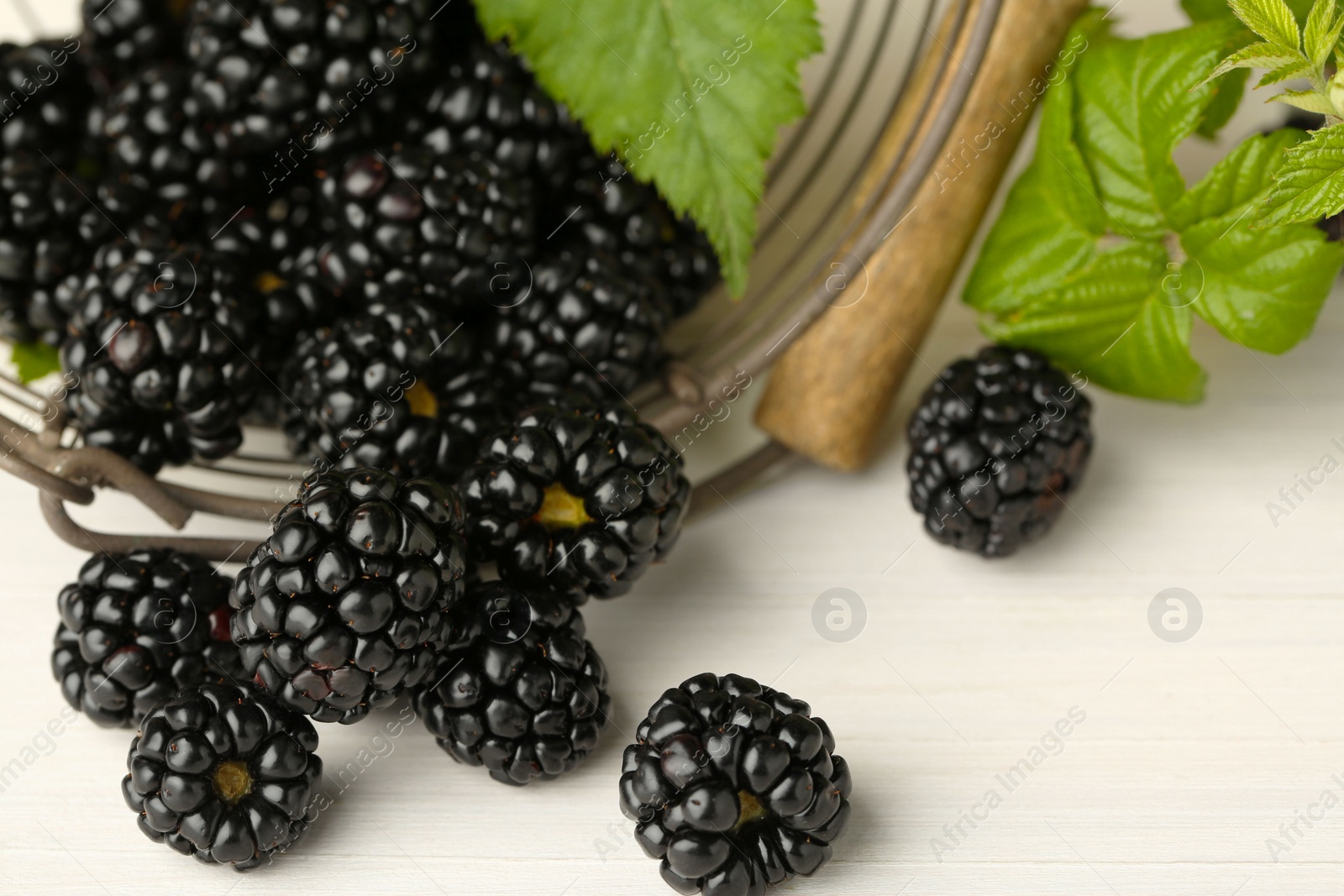 Photo of Fresh ripe blackberries on white wooden table, closeup