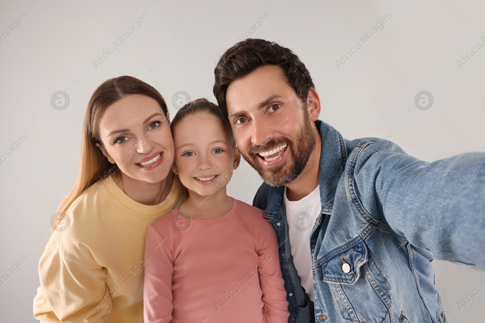 Photo of Happy family taking selfie on light grey background