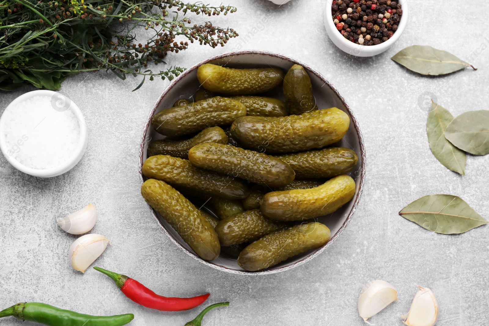 Photo of Pickled cucumbers and ingredients on light grey table, flat lay