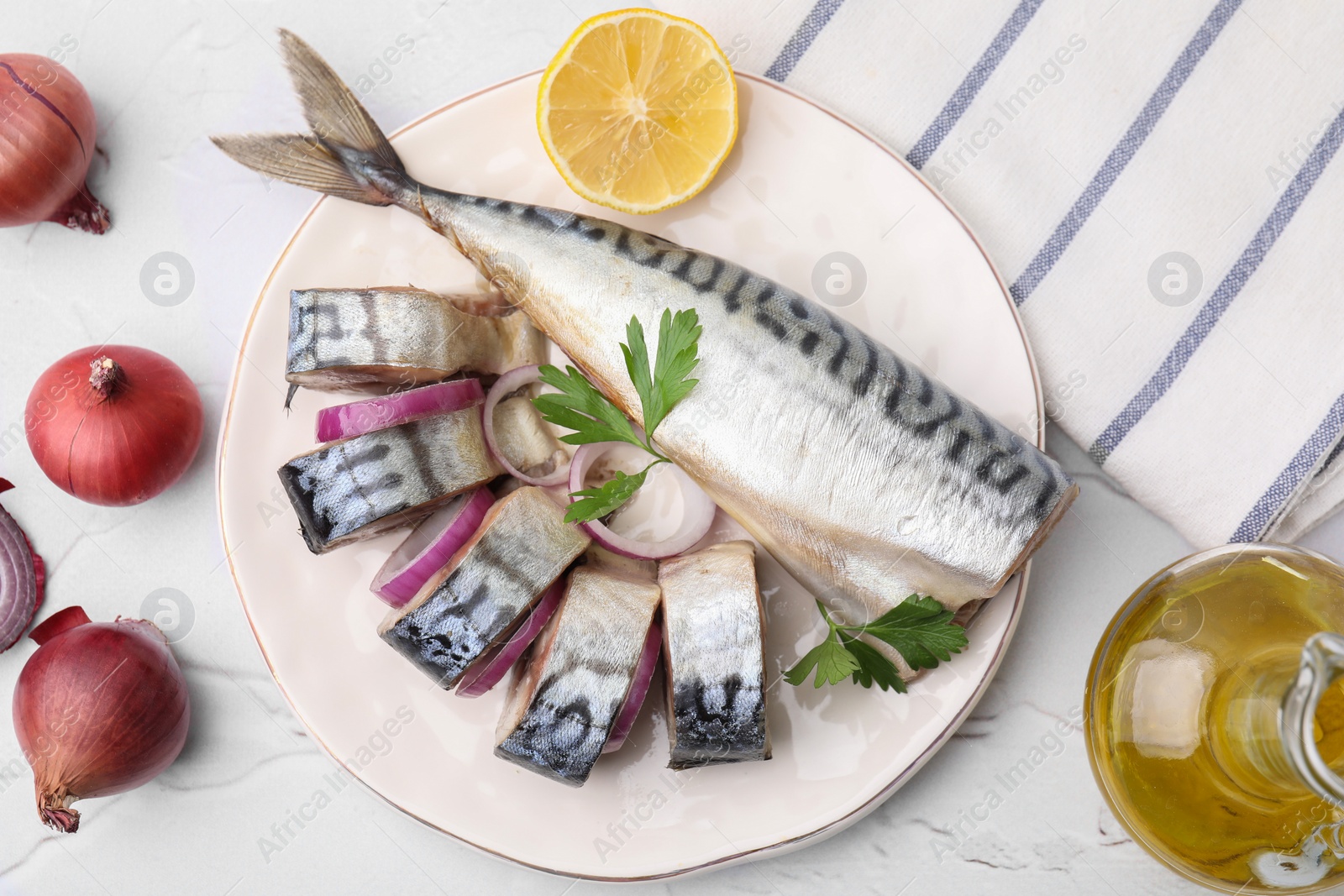 Photo of Tasty salted mackerel, parsley, onion and lemon on white textured table, flat lay