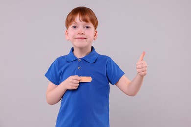 Photo of Little boy with sticking tape showing thumb up on light grey background