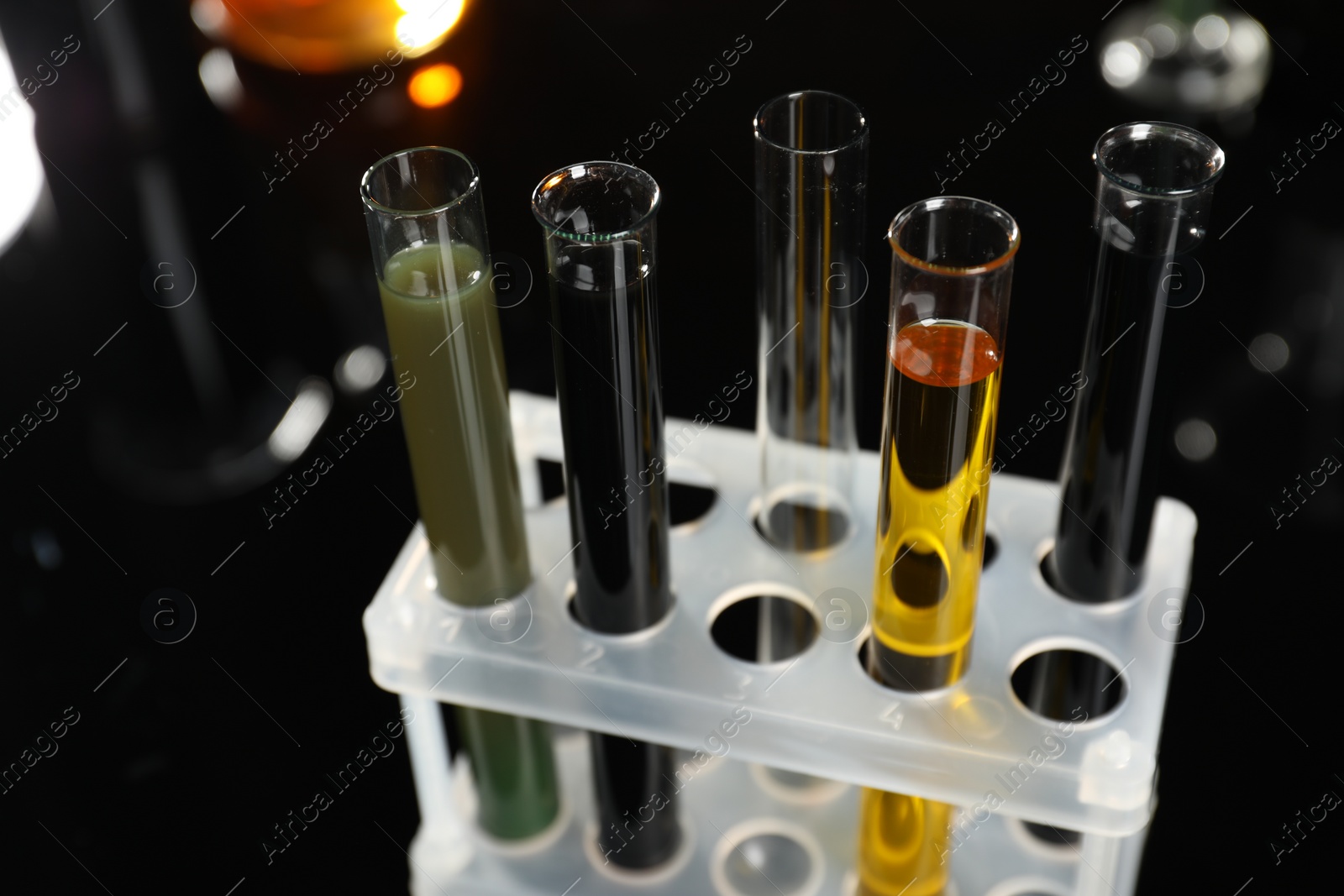 Photo of Test tubes with different types of oil on black background, closeup