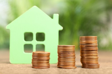 Photo of Mortgage concept. House model and stackscoins on wooden table against blurred green background