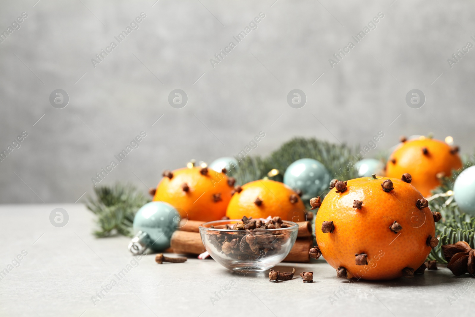 Photo of Delicious fresh tangerines with cloves on light table, space for text. Christmas celebration