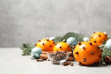 Photo of Delicious fresh tangerines with cloves on light table, space for text. Christmas celebration