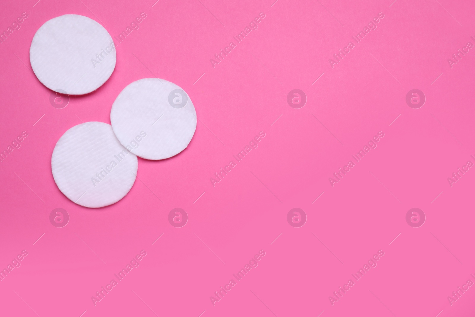 Photo of Cotton pads on pink background, flat lay. Space for text