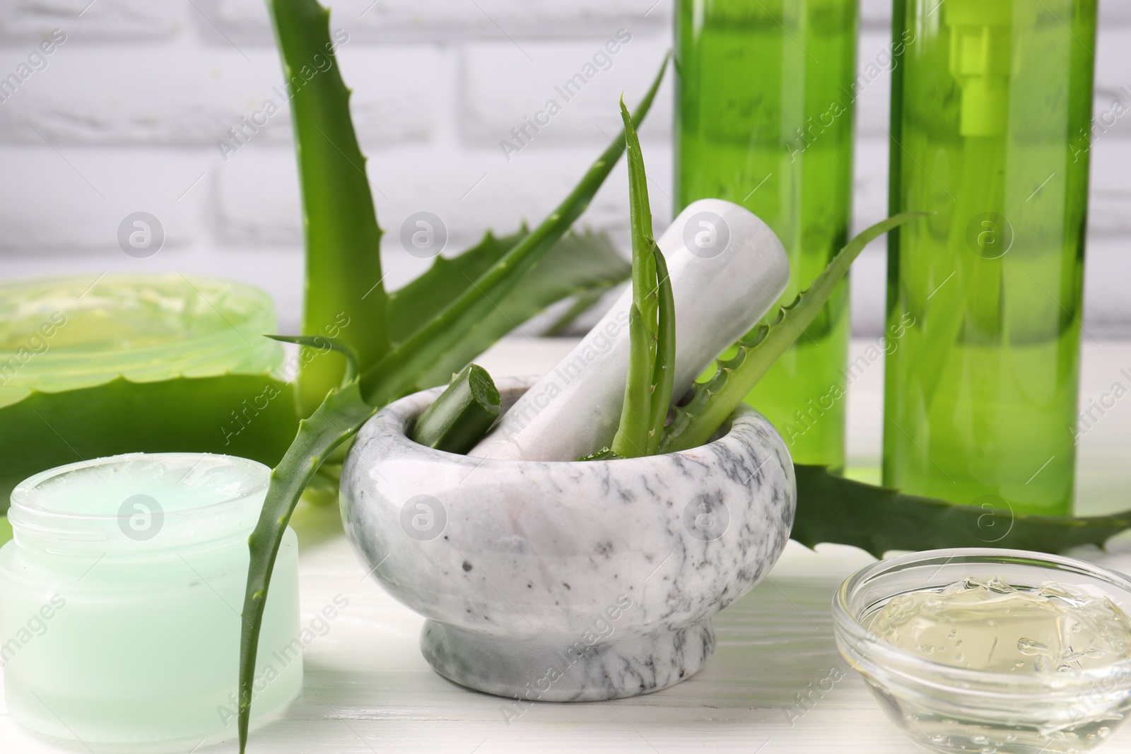 Photo of Homemade aloe gel and fresh ingredients on white wooden table, closeup