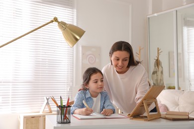 Mother helping her daughter with homework using tablet at home