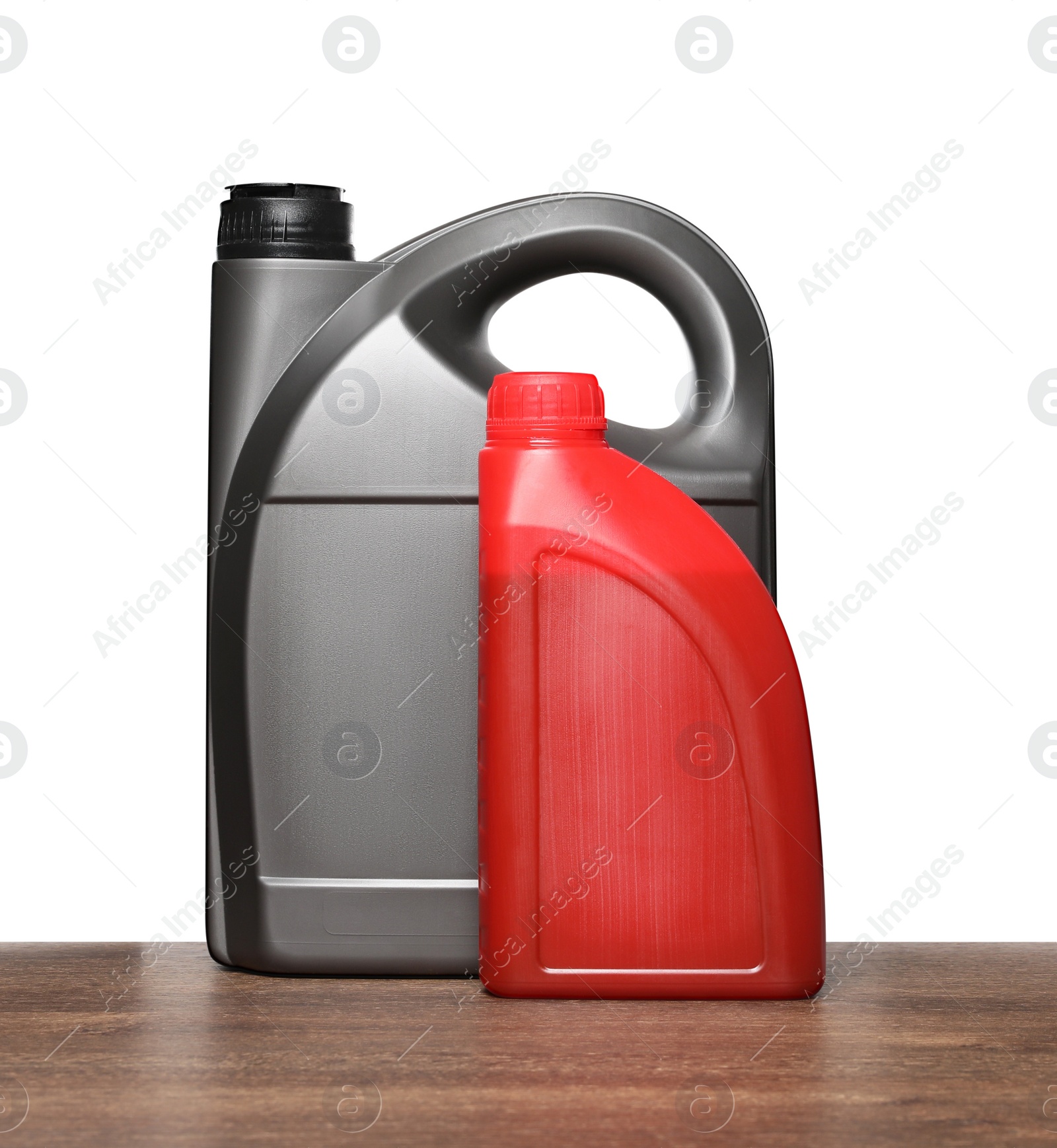 Photo of Motor oil in different containers on wooden table against white background