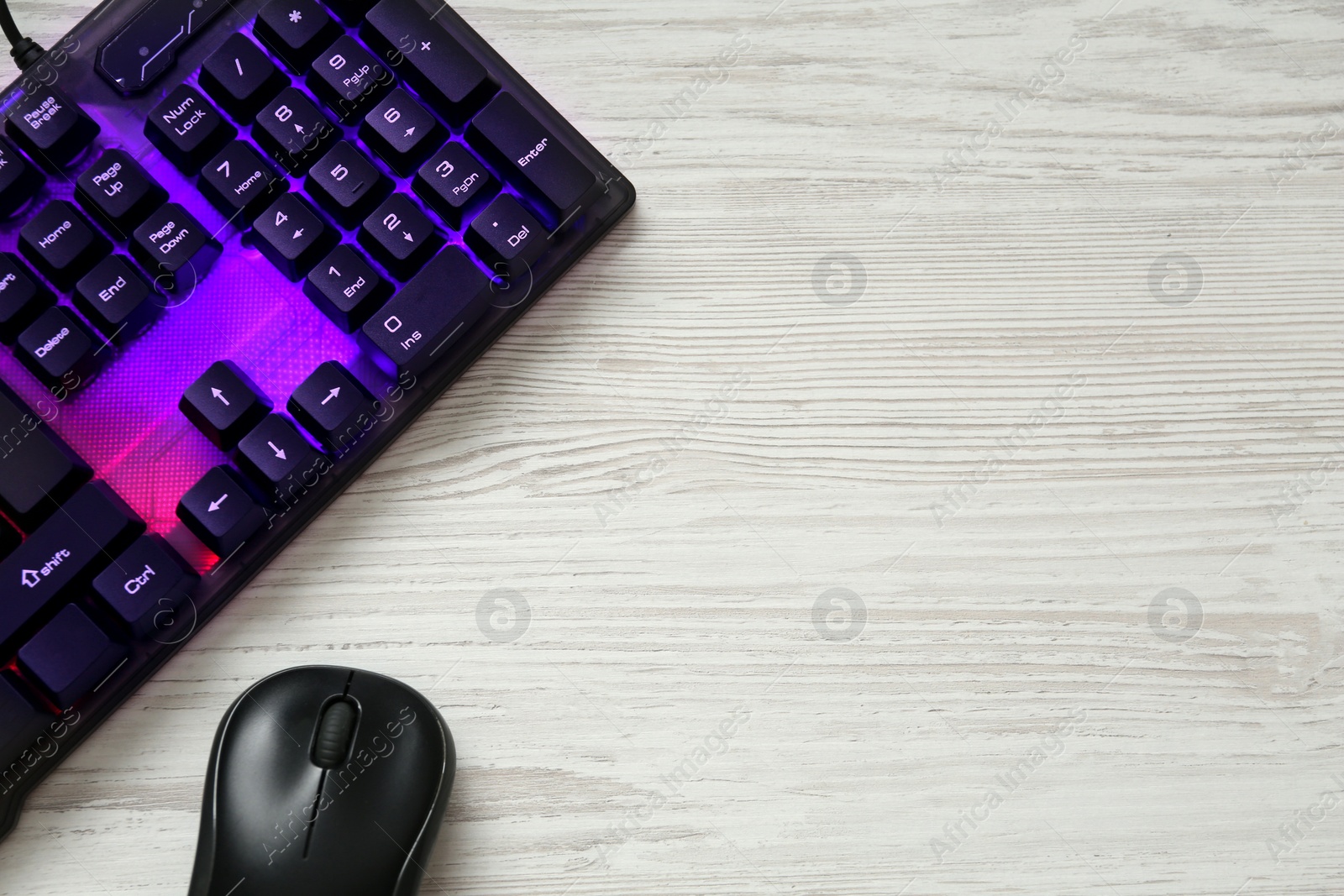 Photo of Modern RGB keyboard and mouse on white wooden table, flat lay. Space for text