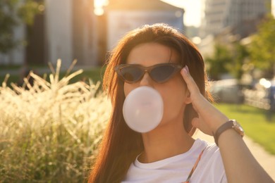 Photo of Beautiful woman blowing gum outdoors, space for text