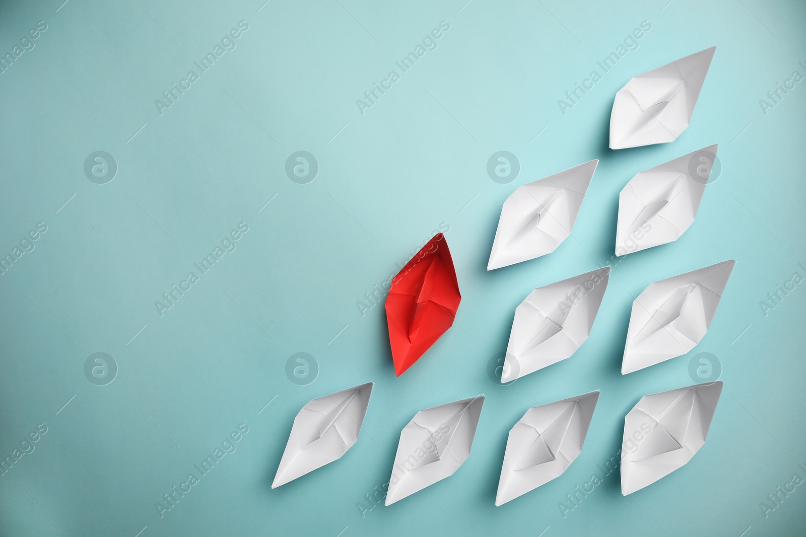 Photo of Red paper boat among others on light background, flat lay with space for text. Uniqueness concept