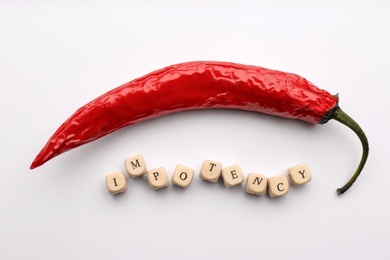 Photo of Chili pepper and cubes with word Impotency on white background, flat lay