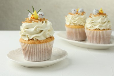 Photo of Tasty Easter cupcakes with vanilla cream on white table