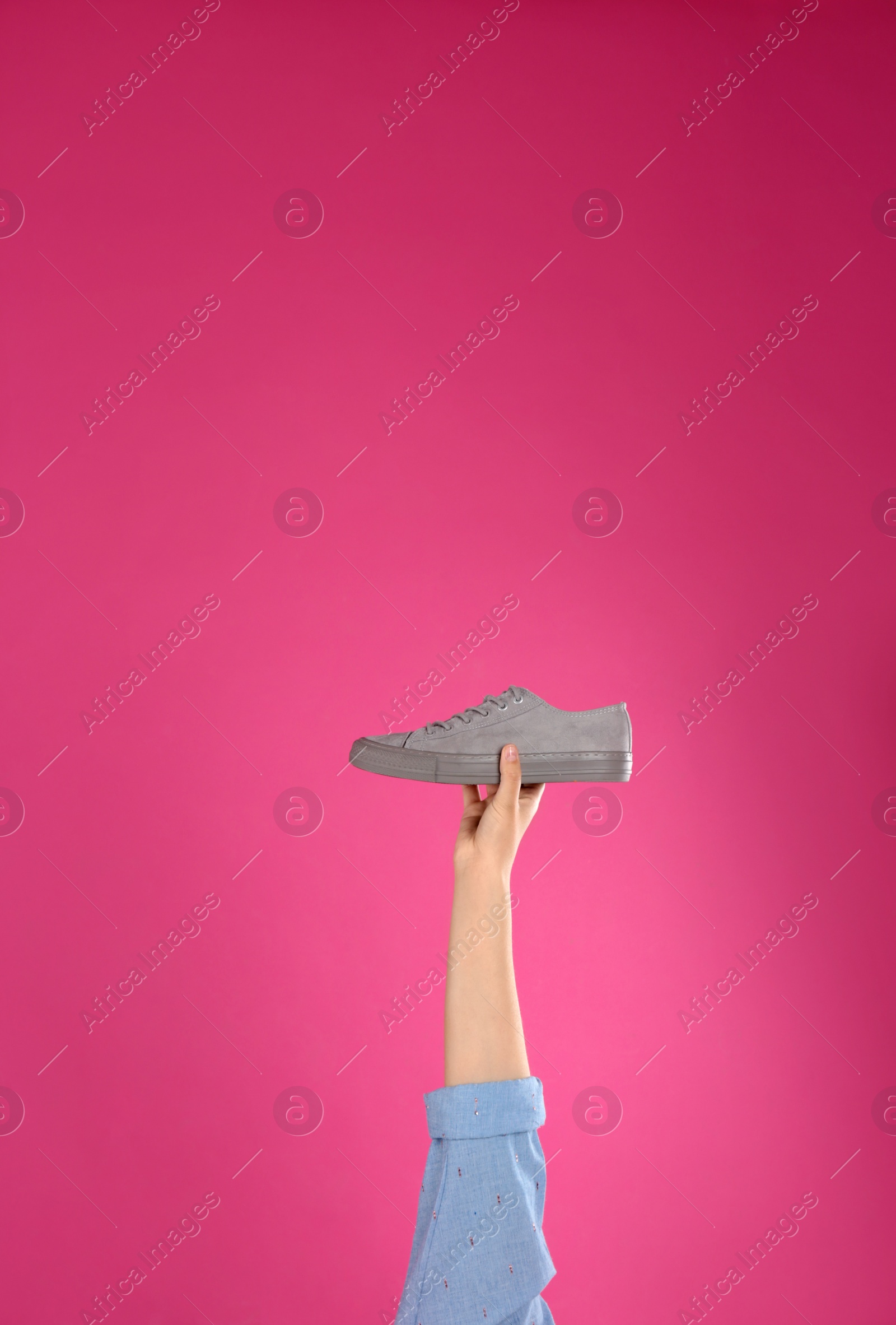 Photo of Young woman holding comfortable shoe on pink background, closeup