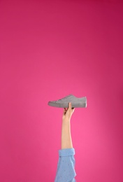 Photo of Young woman holding comfortable shoe on pink background, closeup