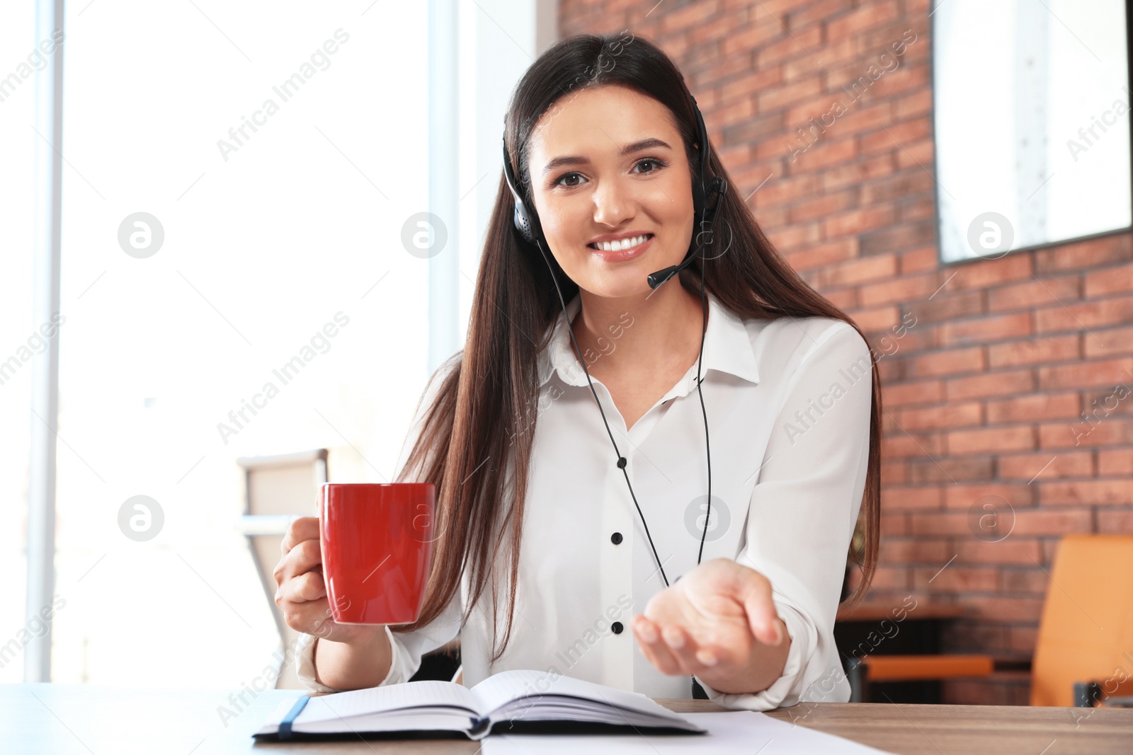 Photo of Young woman with headset looking at camera and using video chat in home office