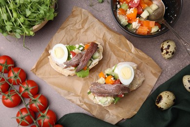 Delicious bruschettas with anchovies, eggs, cream cheese, tomatoes, bell peppers and cucumbers on grey table, flat lay