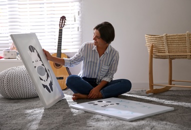 Photo of Decorator with pictures on floor in baby room. Interior design