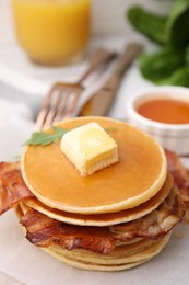 Delicious pancakes with bacon, butter and honey on table, closeup