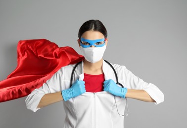 Photo of Doctor dressed as superhero posing on light grey background. Concept of medical workers fighting with COVID-19