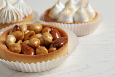 Photo of Different tartlets on white wooden table, closeup with space for text. Tasty dessert