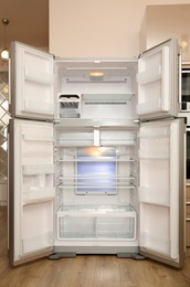 Empty modern refrigerator with open doors in kitchen