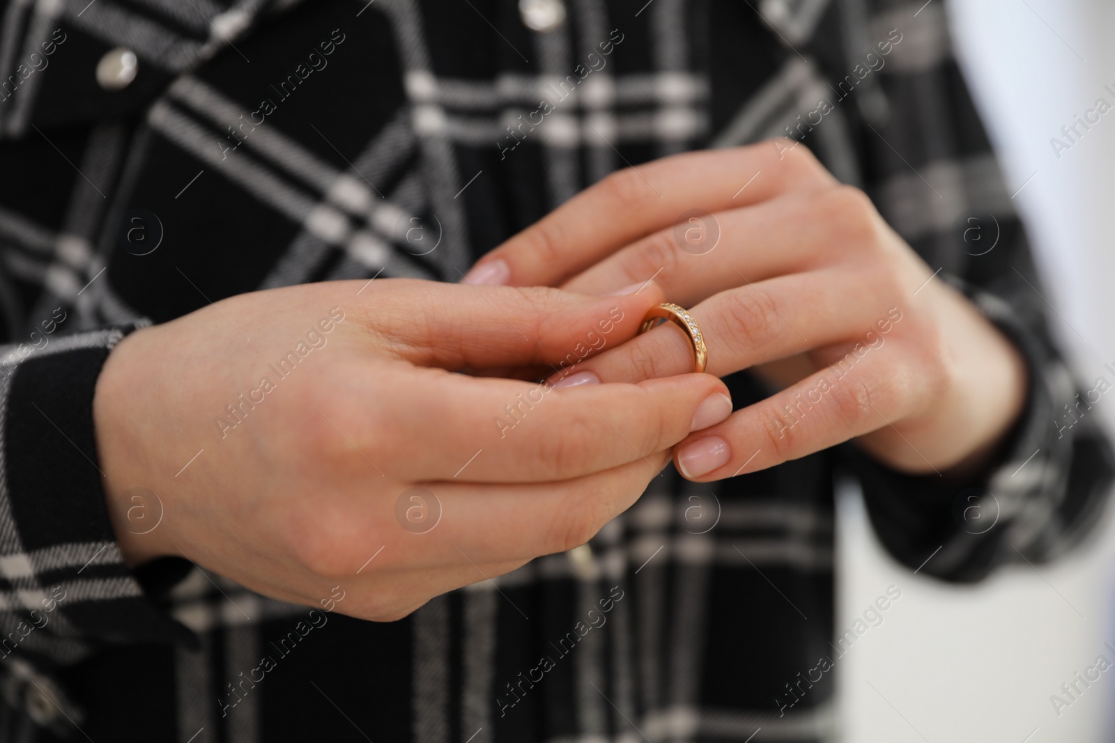 Photo of Woman taking off wedding ring on grey background, closeup. Divorce concept