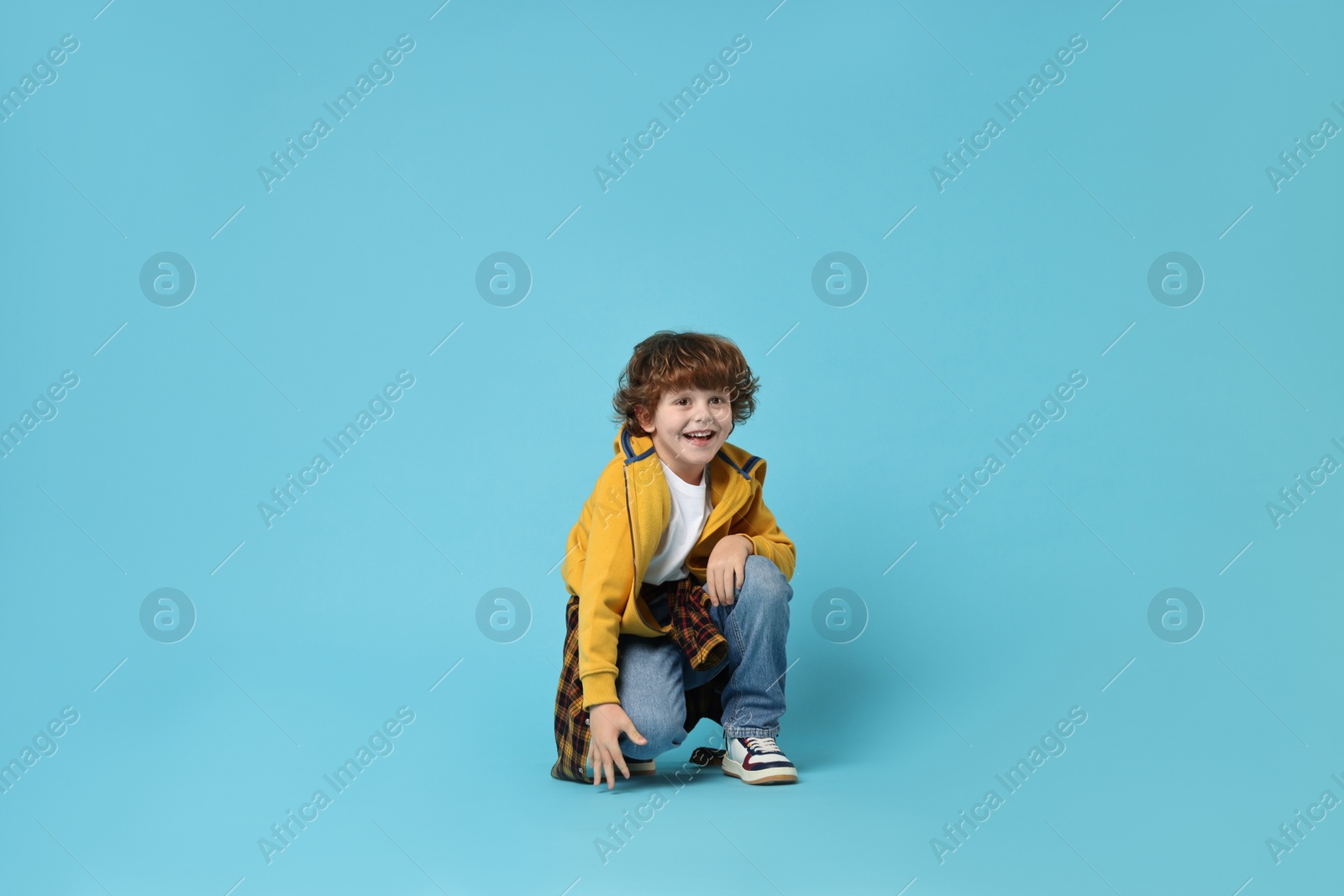 Photo of Happy little boy dancing on light blue background