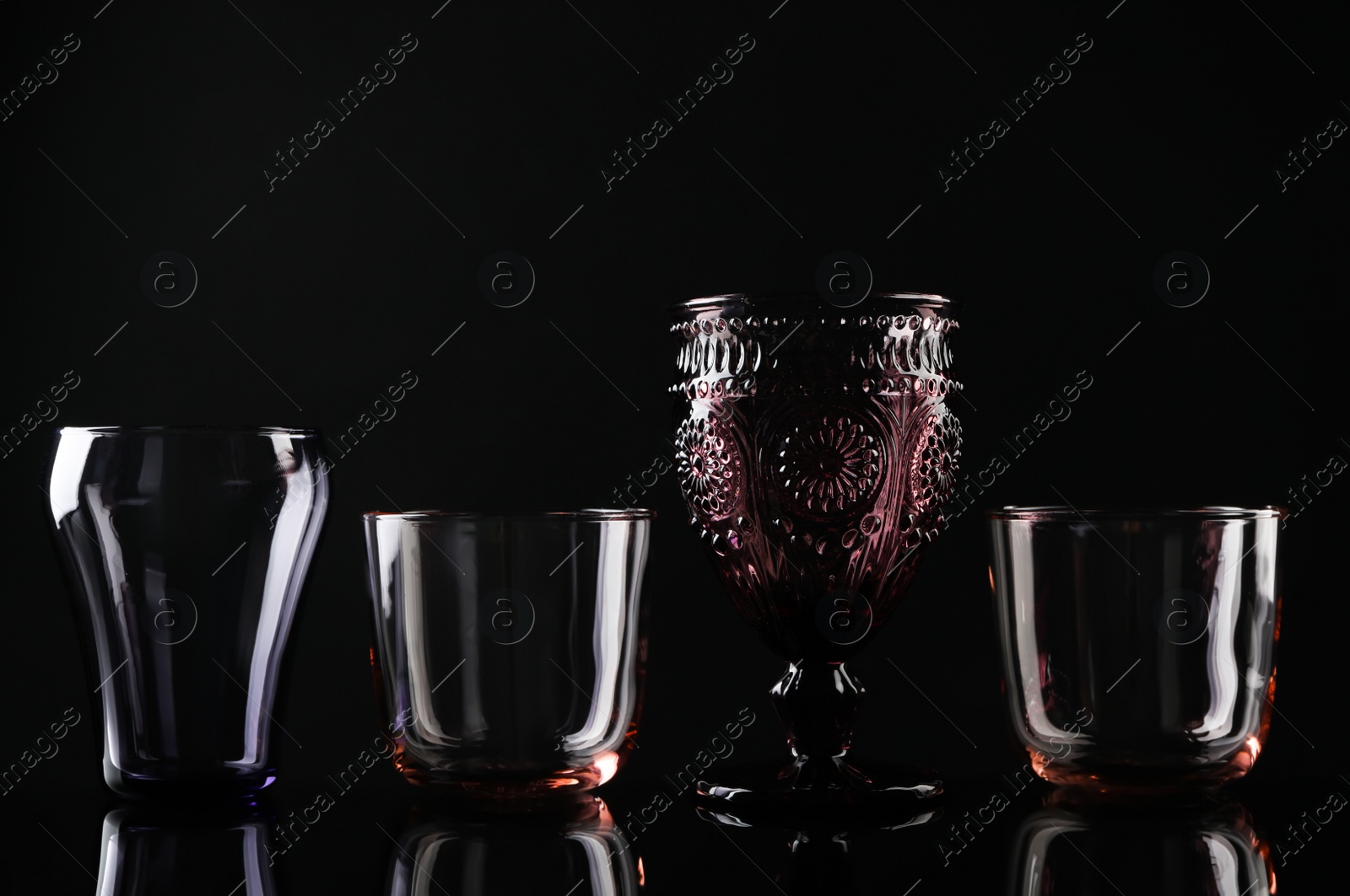 Photo of Set of different colorful empty glasses on black background