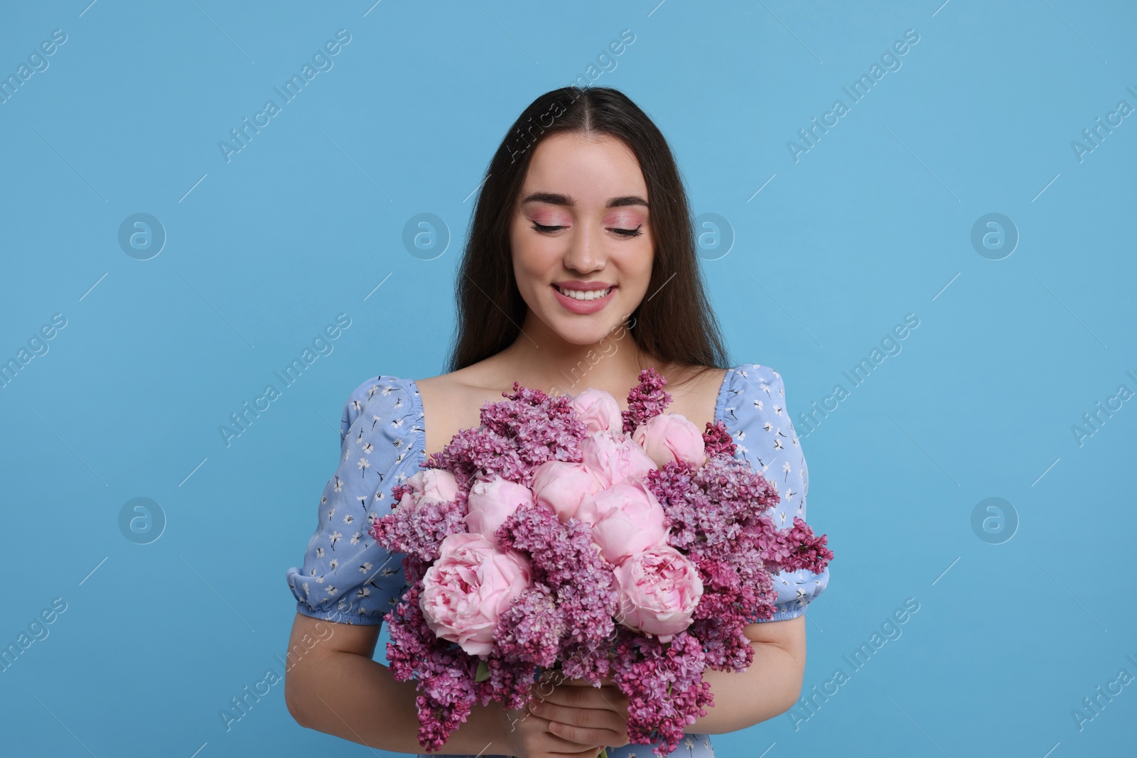 Photo of Beautiful woman with bouquet of spring flowers on light blue background