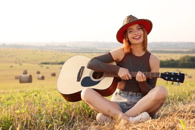 Beautiful happy hippie woman with guitar in field, space for text