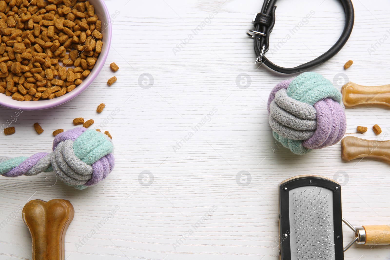 Photo of Flat lay composition with dog toys, food and accessories on white wooden table. Space for text