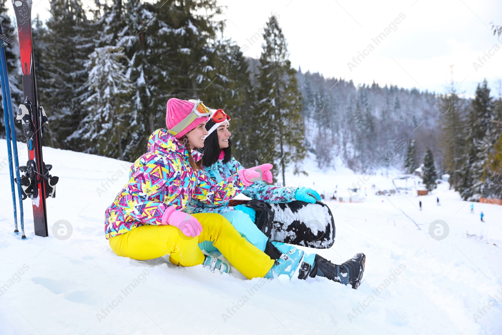 Photo of Friends resting on hill at mountain resort. Winter vacation