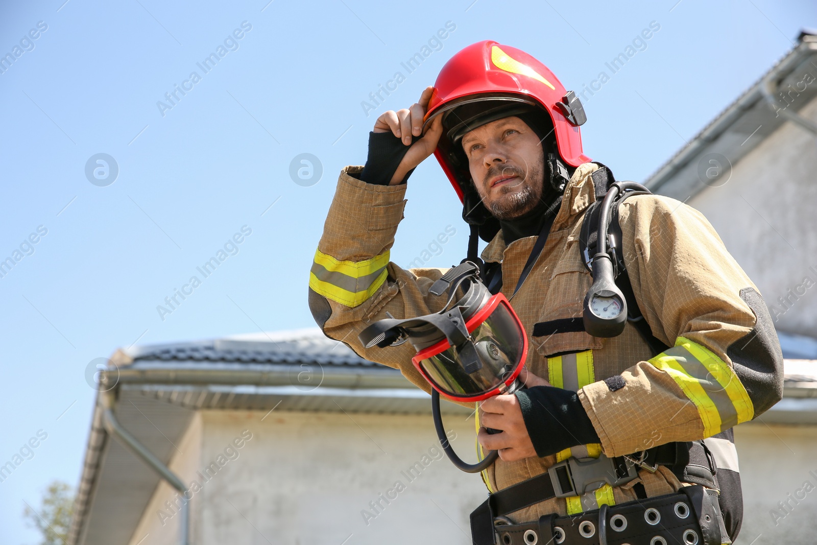 Photo of Firefighter in uniform with helmet and mask outdoors, low angle view