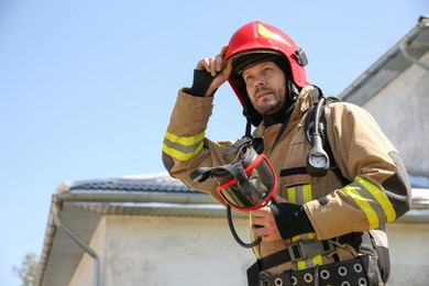 Photo of Firefighter in uniform with helmet and mask outdoors, low angle view