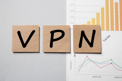 Photo of Paper notes with acronym VPN (Virtual Private Network) and document on light grey background, flat lay