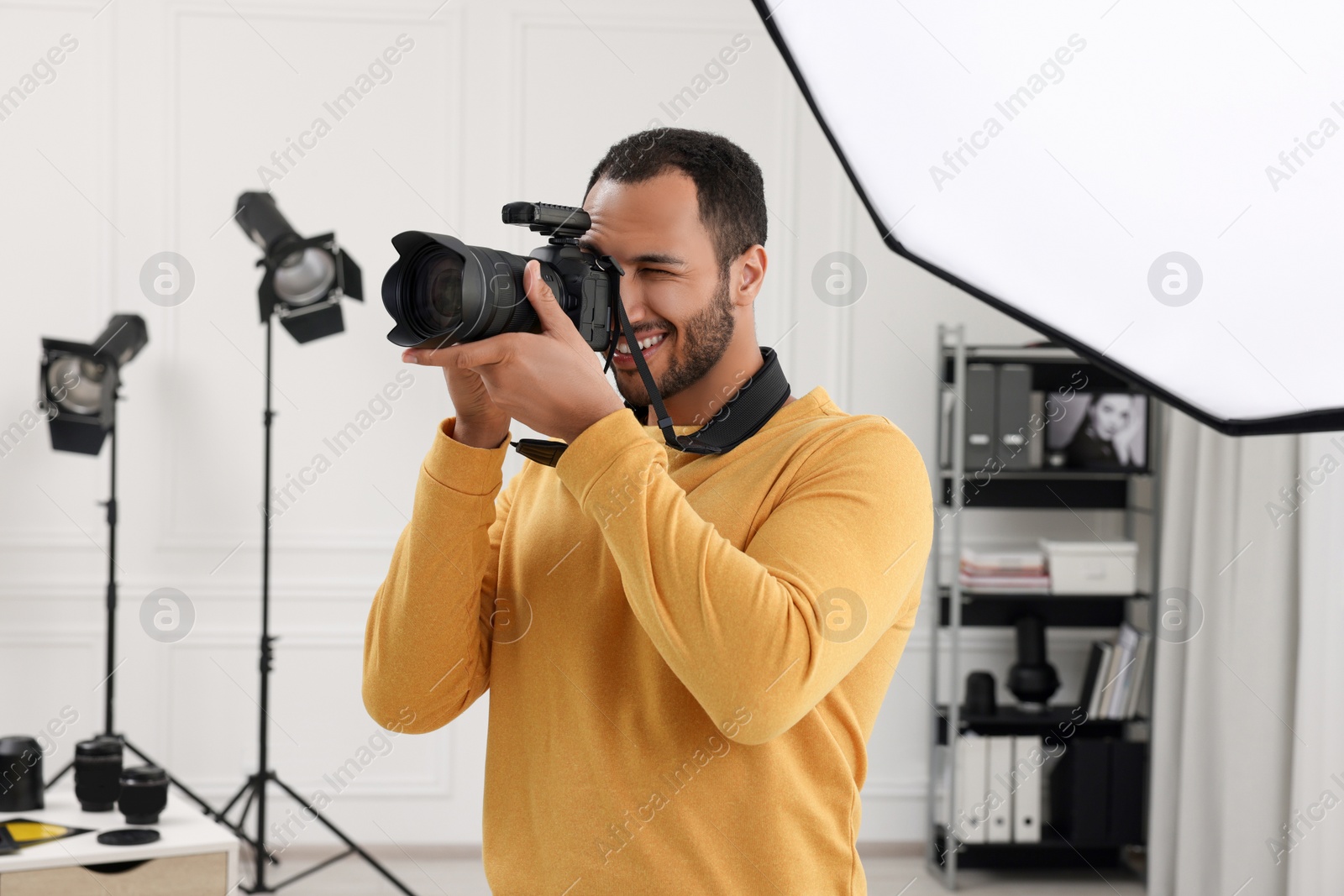 Photo of Young professional photographer taking picture in modern photo studio