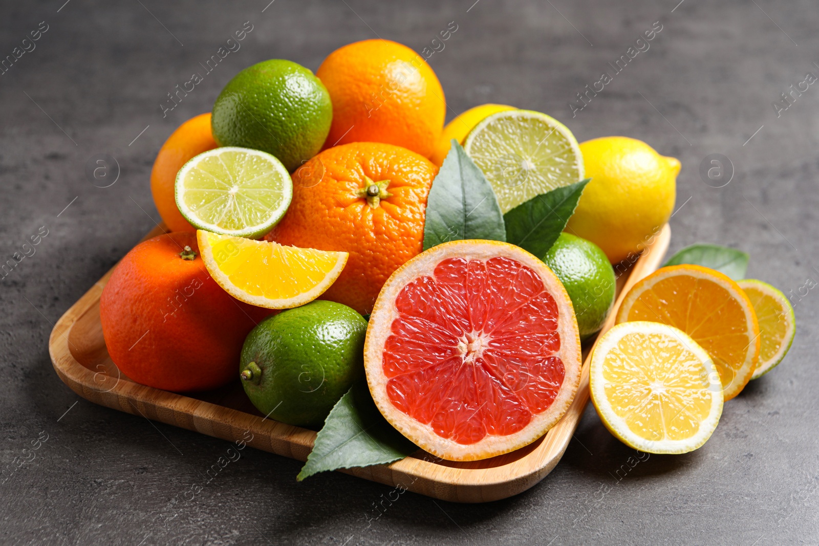 Photo of Different ripe citrus fruits on black table