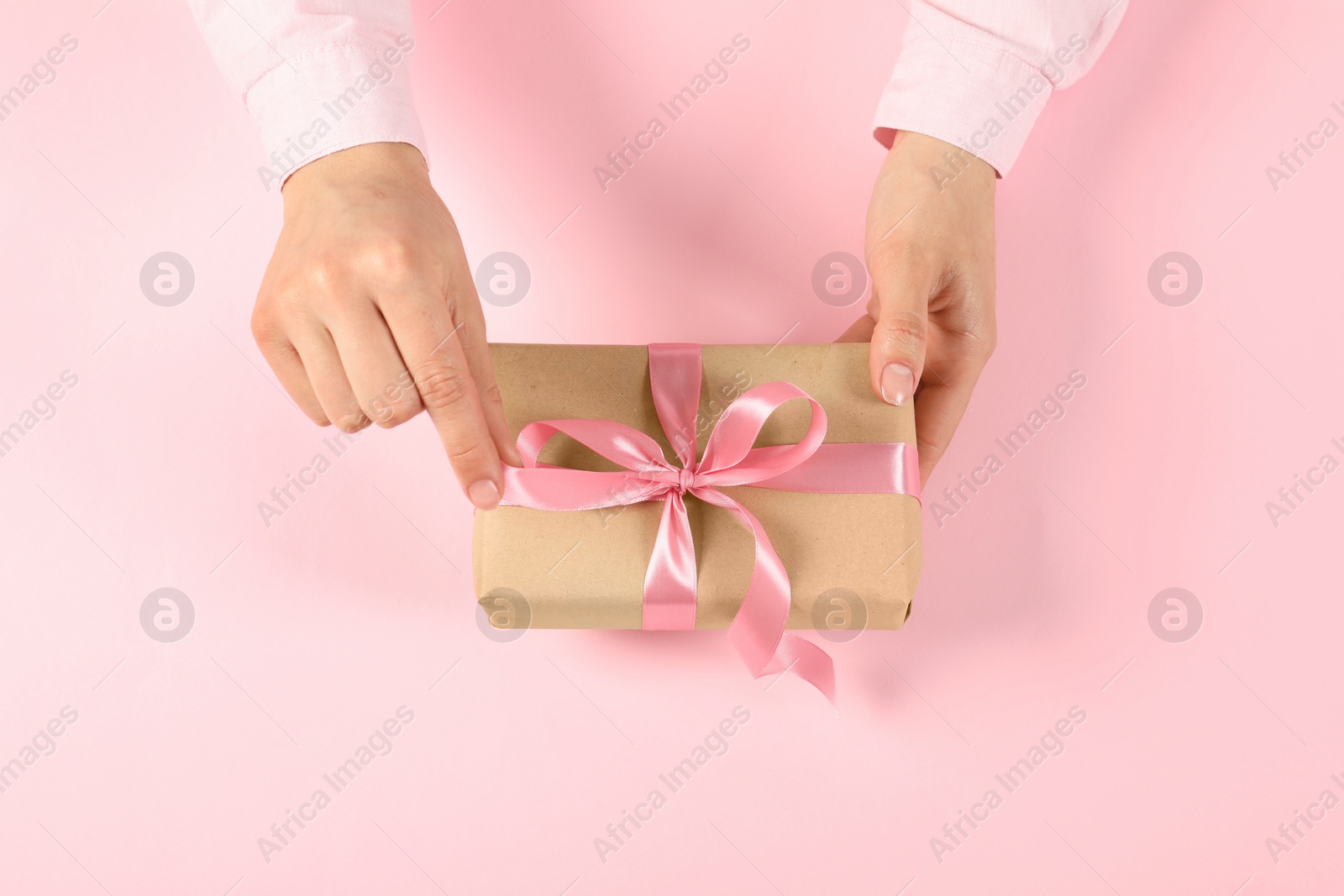 Photo of Woman with gift box on pink background, top view