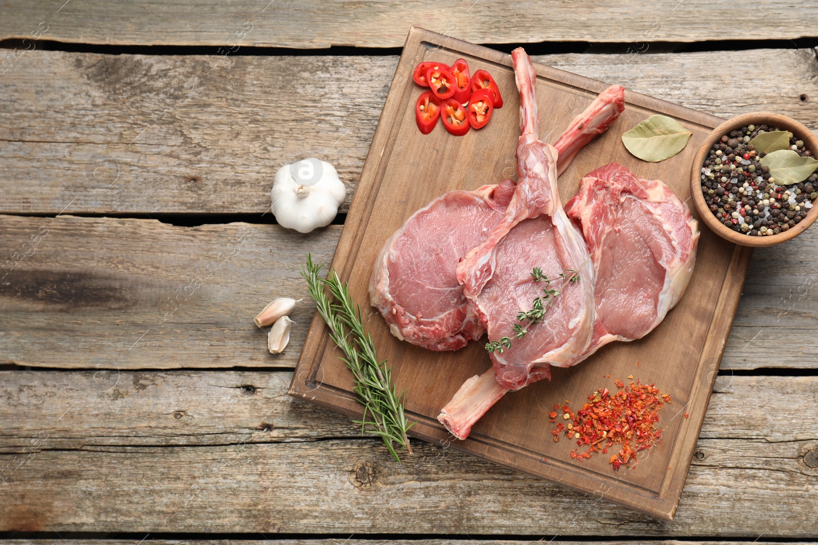 Photo of Fresh tomahawk beef cuts and spices on wooden table, top view. Space for text