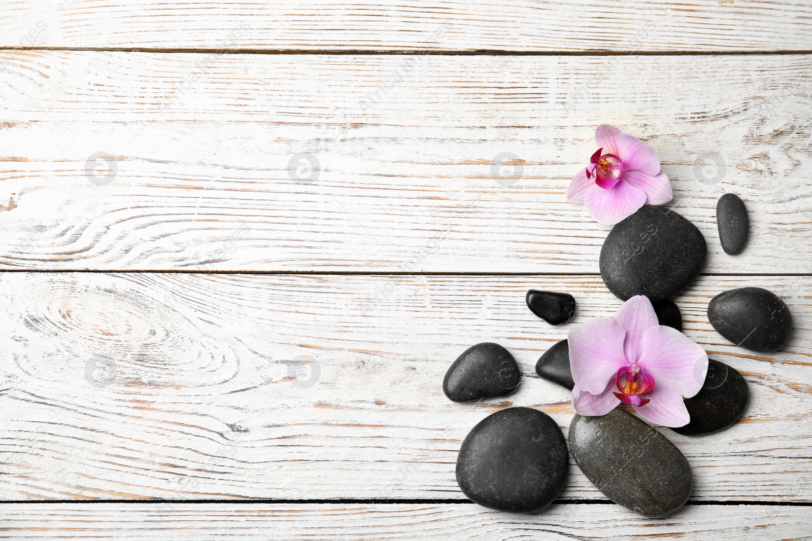 Photo of Stones with orchid flowers and space for text on white wooden background, flat lay. Zen lifestyle