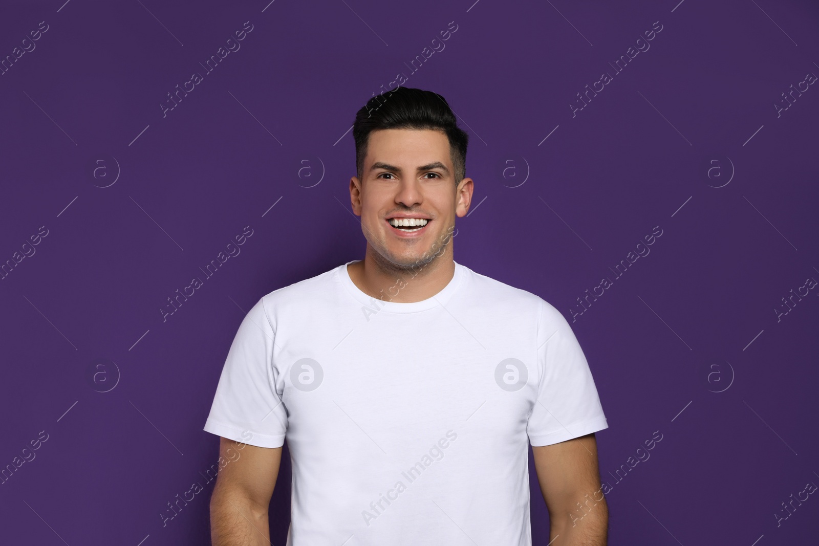 Photo of Handsome man laughing on purple background. Funny joke