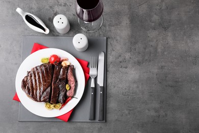 Photo of Delicious grilled beef meat served on grey table, flat lay. Space for text