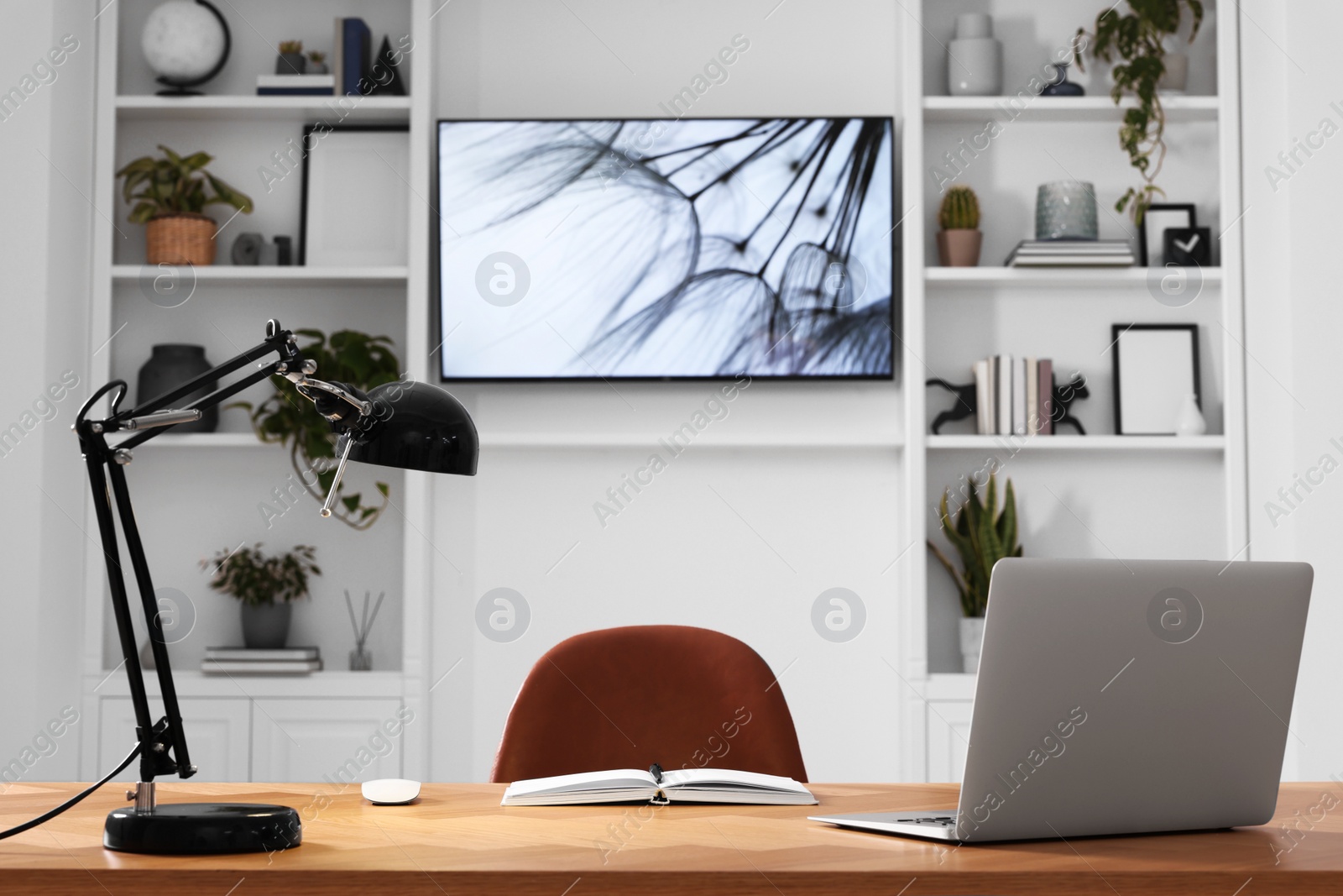 Photo of Cosy workplace with laptop near tv area. Interior design