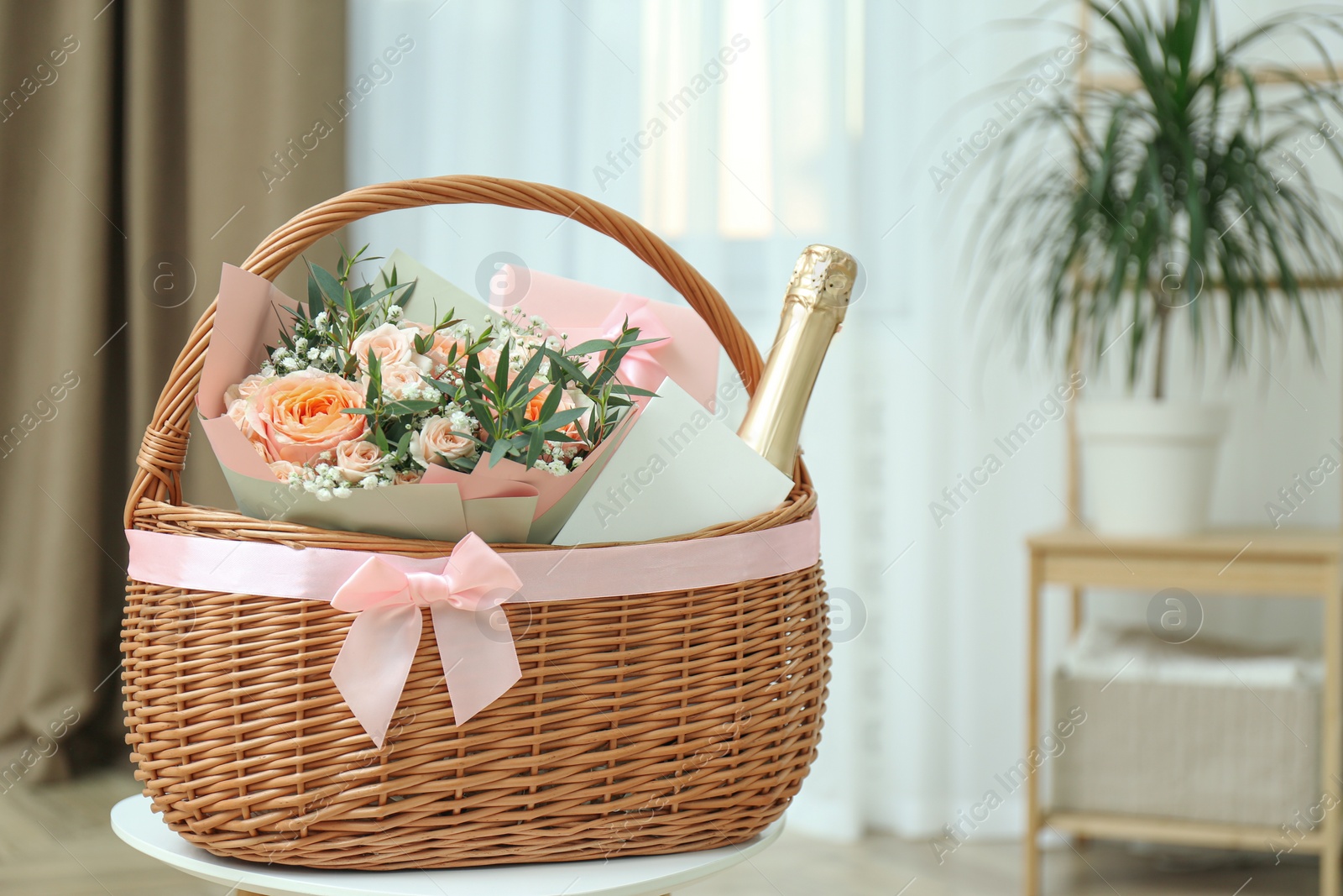 Photo of Wicker basket with gifts on table indoors