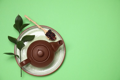 Photo of Flat lay composition with teapot and wooden spoon on green background. Space for text