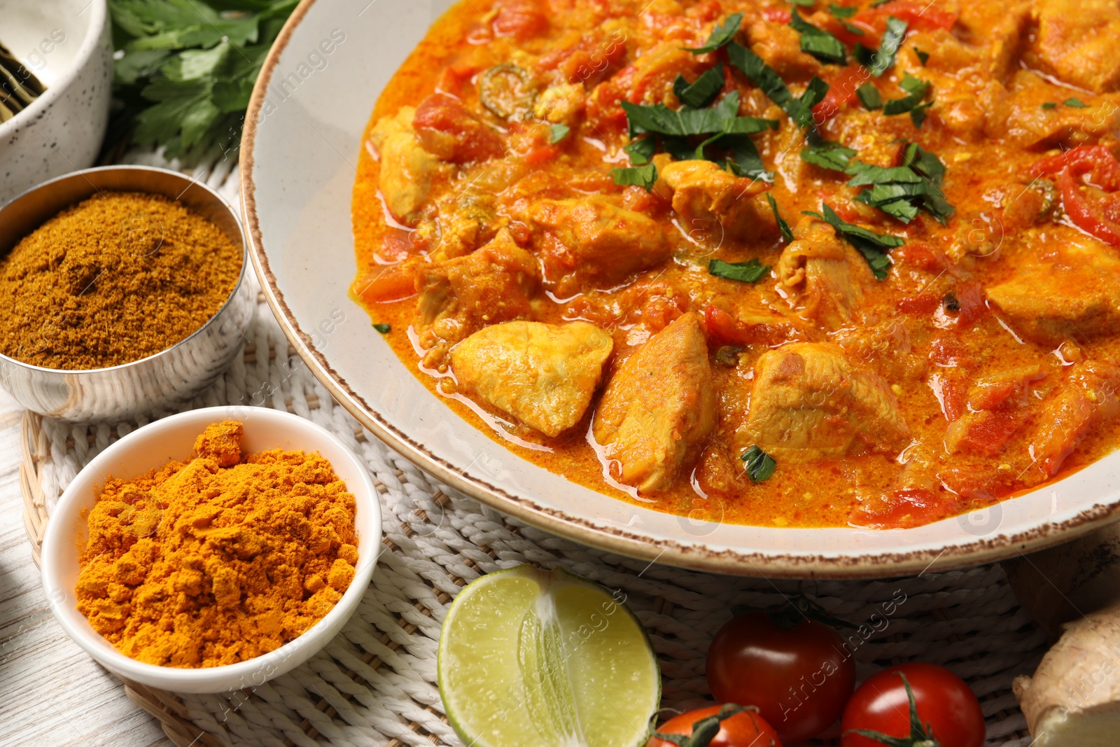 Photo of Delicious chicken curry and ingredients on table, closeup