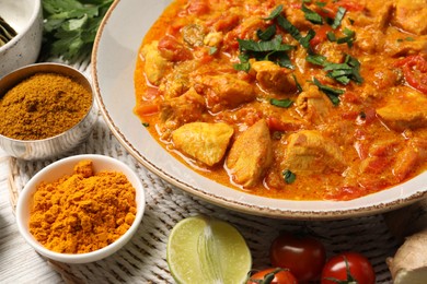 Delicious chicken curry and ingredients on table, closeup